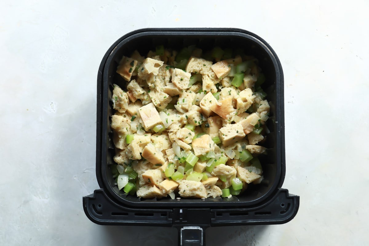 Uncooked stuffing mix in an air fryer basket.