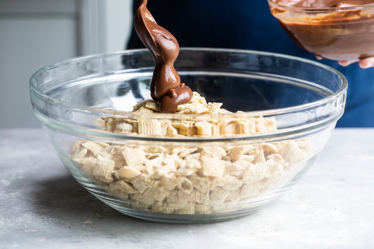 Making puppy chow in a clear glass bowl.