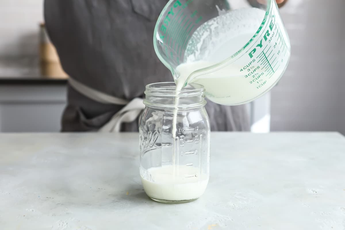 Creme fraiche liquid being poured into a mason jar.
