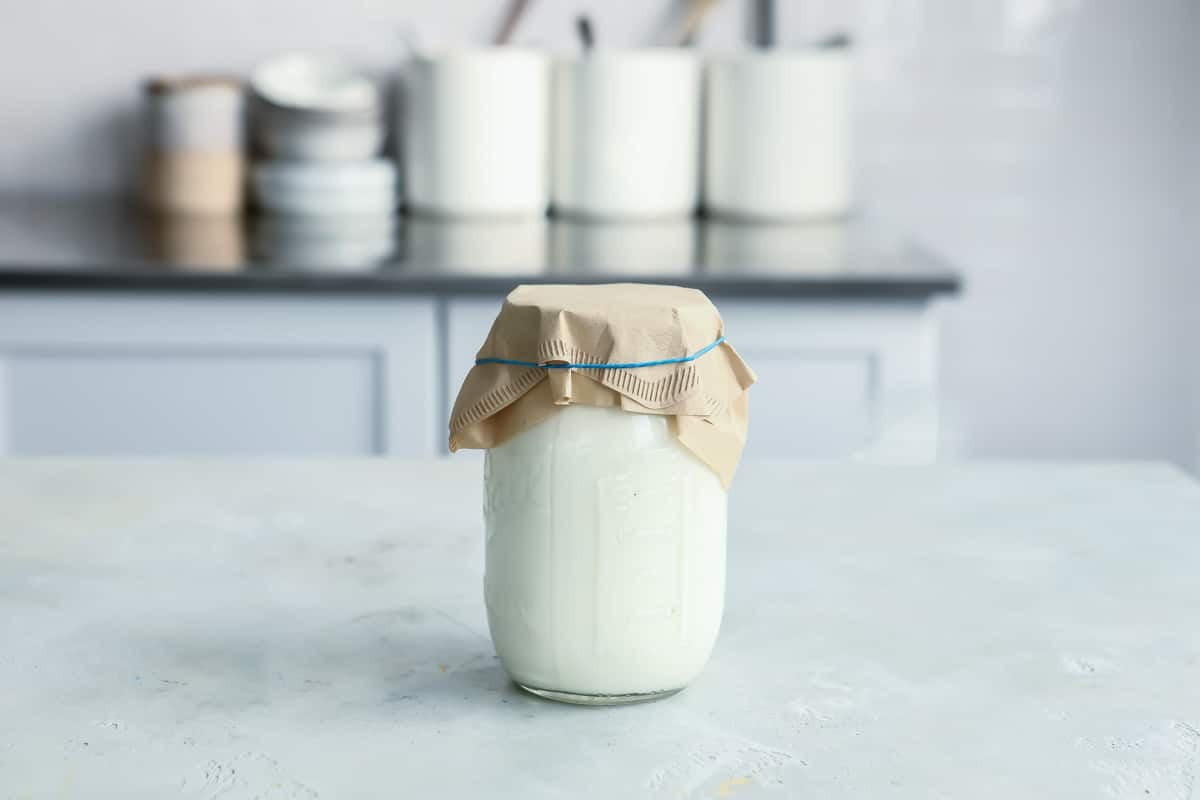 A mason jar of creme fraiche being made.
