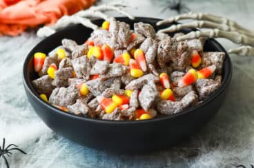 A bowl of Halloween puppy chow with two plastic skeletal hands reaching into it.