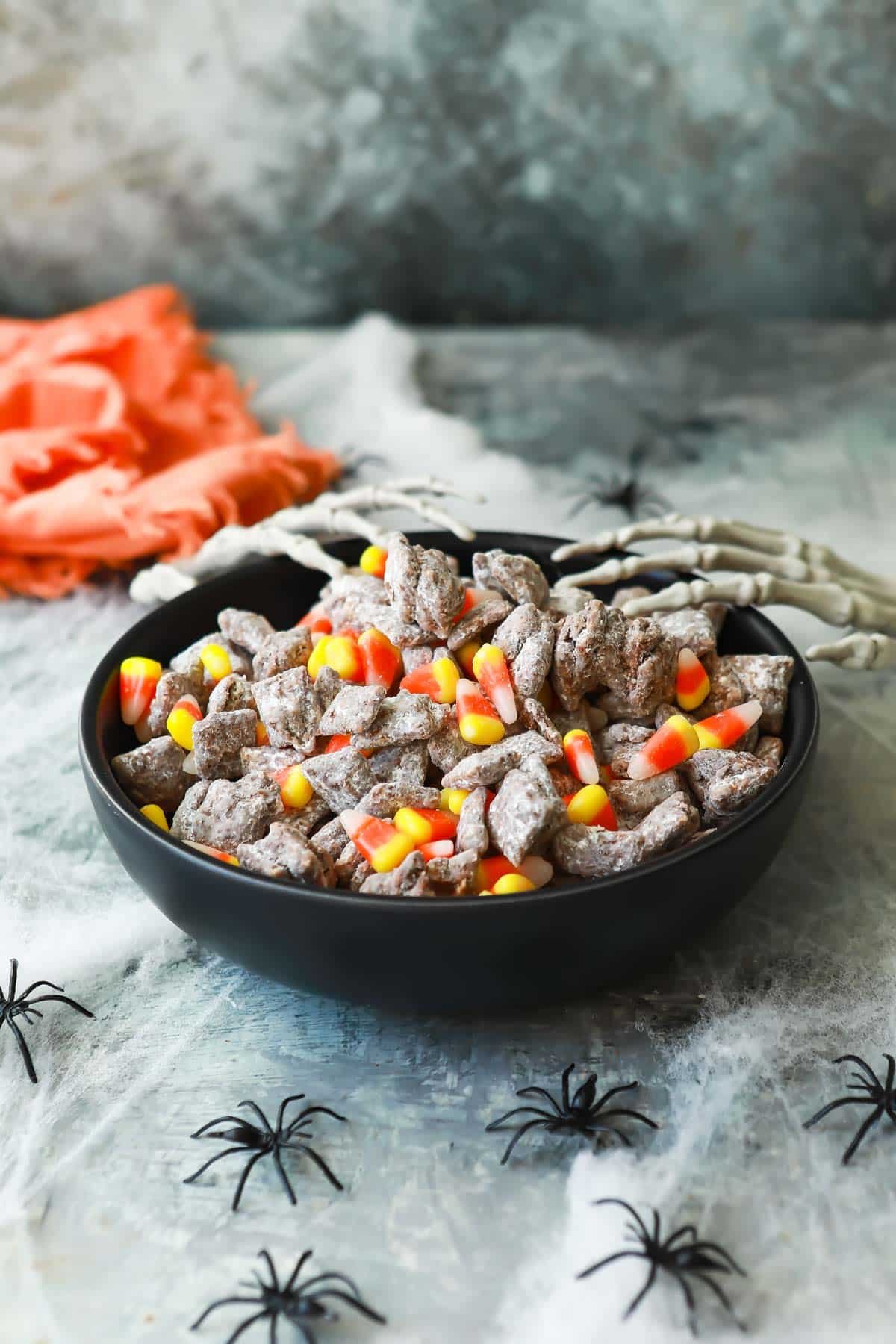 A bowl of Halloween puppy chow with two plastic skeletal hands reaching into it.