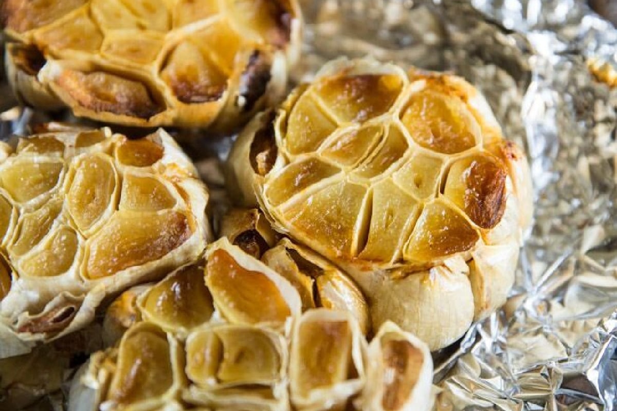 Bulbs of roasted garlic on foil.