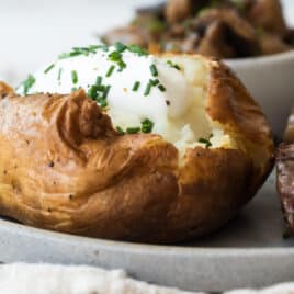 A baked potato topped with sour cream and chives.