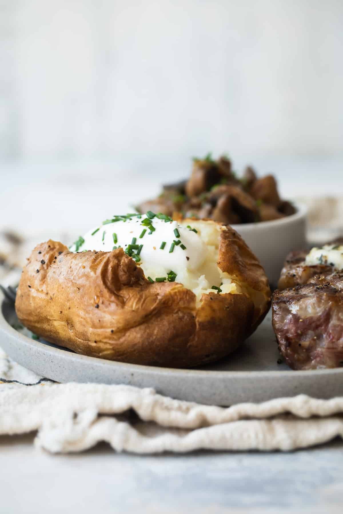 A baked potato topped with sour cream and chives.