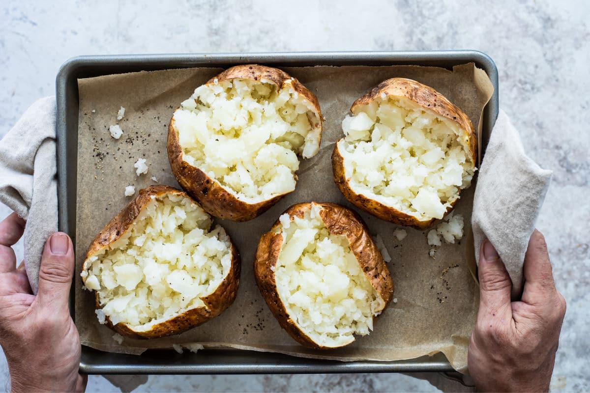 4 cooked potatoes on a baking sheet.
