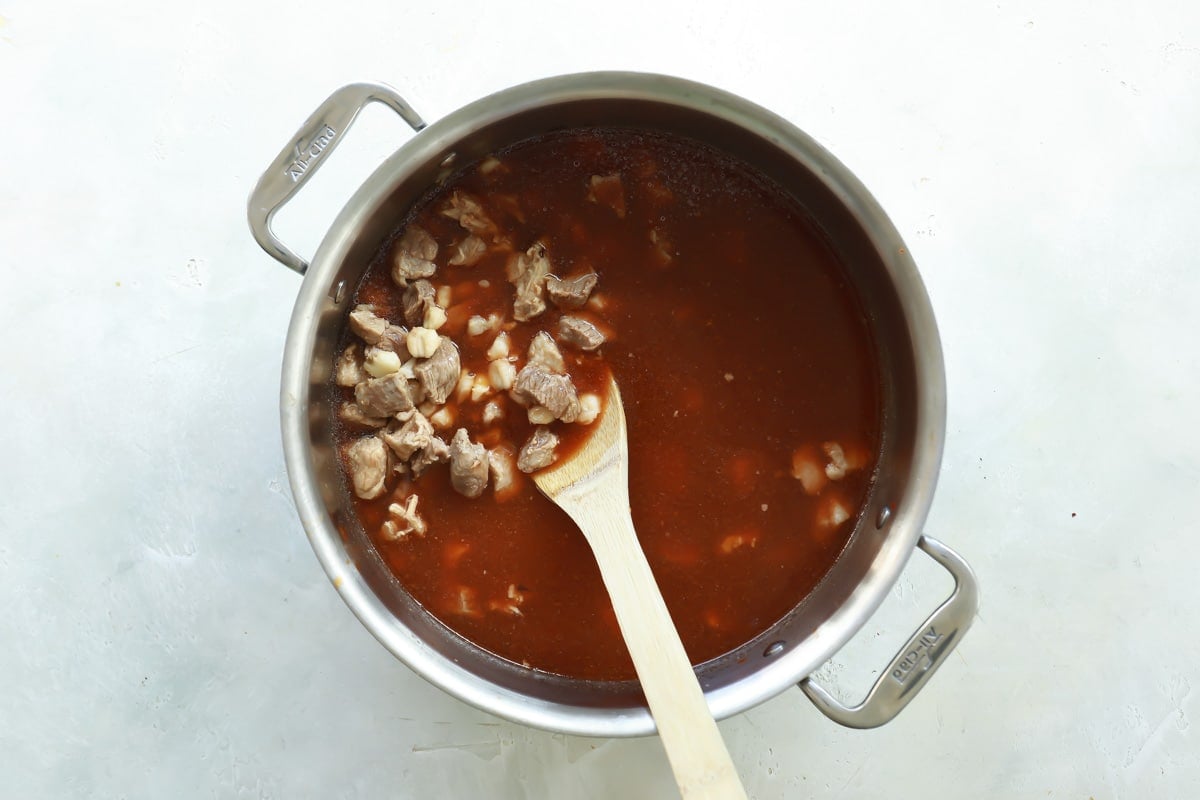 A pot of pozole rojo being stirred.