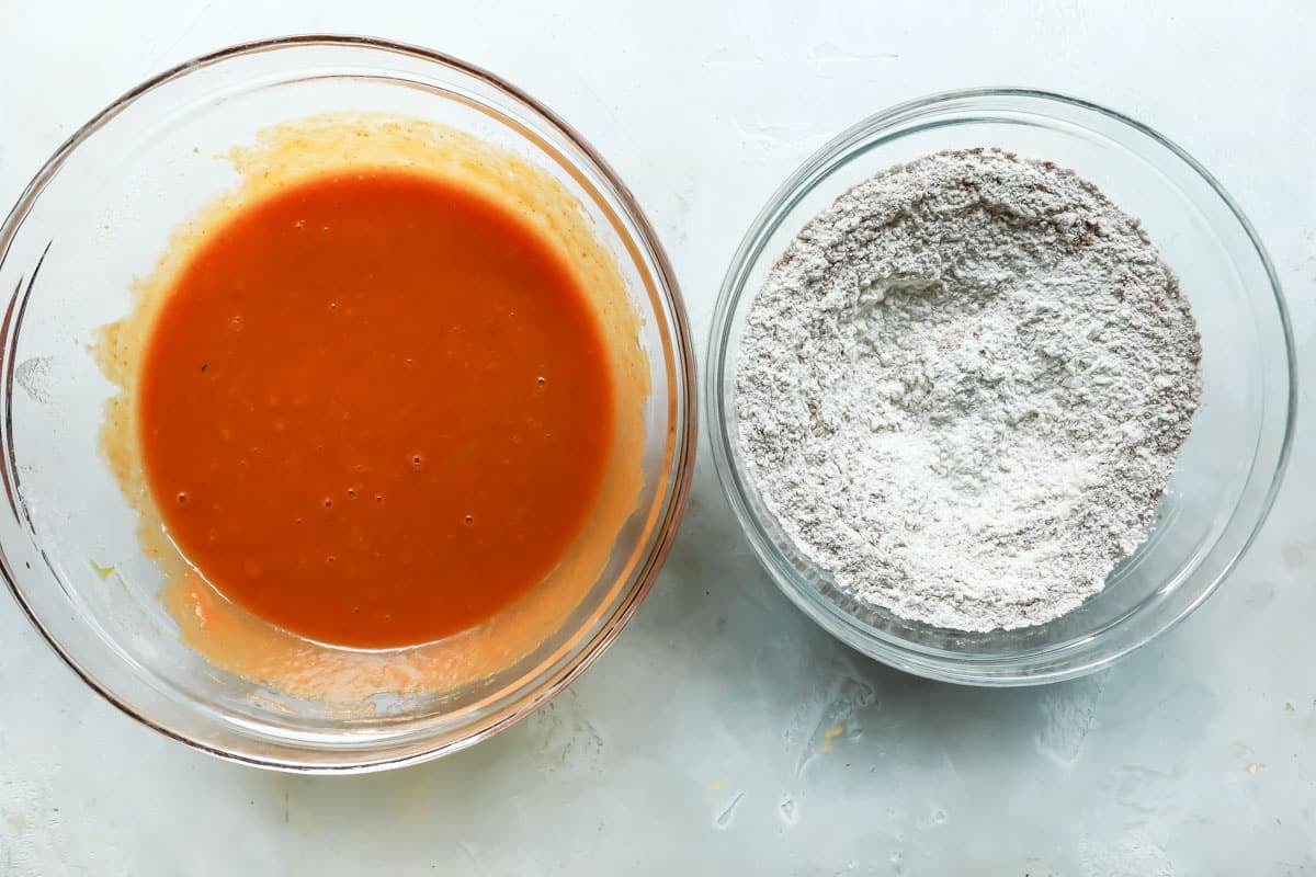 A bowl of wet pumpkin bread ingredients next a bowl of dry pumpkin bread ingredients.