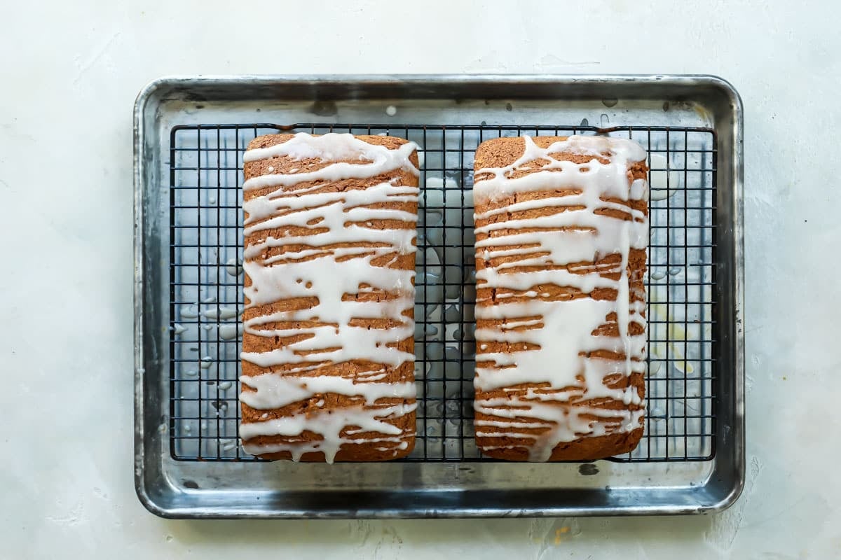 Pumpkin bread on cooling racks after having icing drizzled on top.