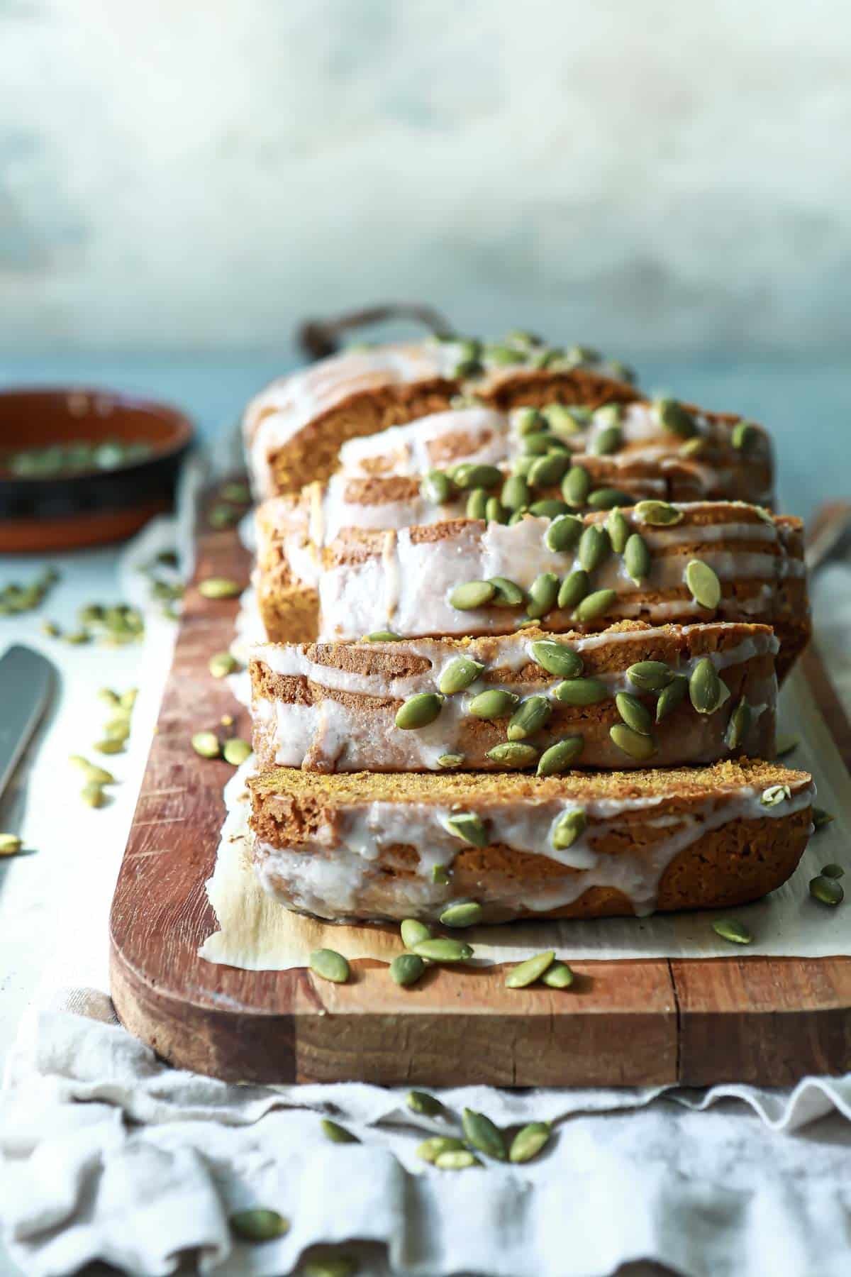 A loaf of pumpkin bread sliced on a wooden cutting board.