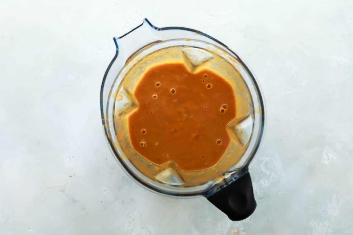 A blender with pumpkin soup ingredients.