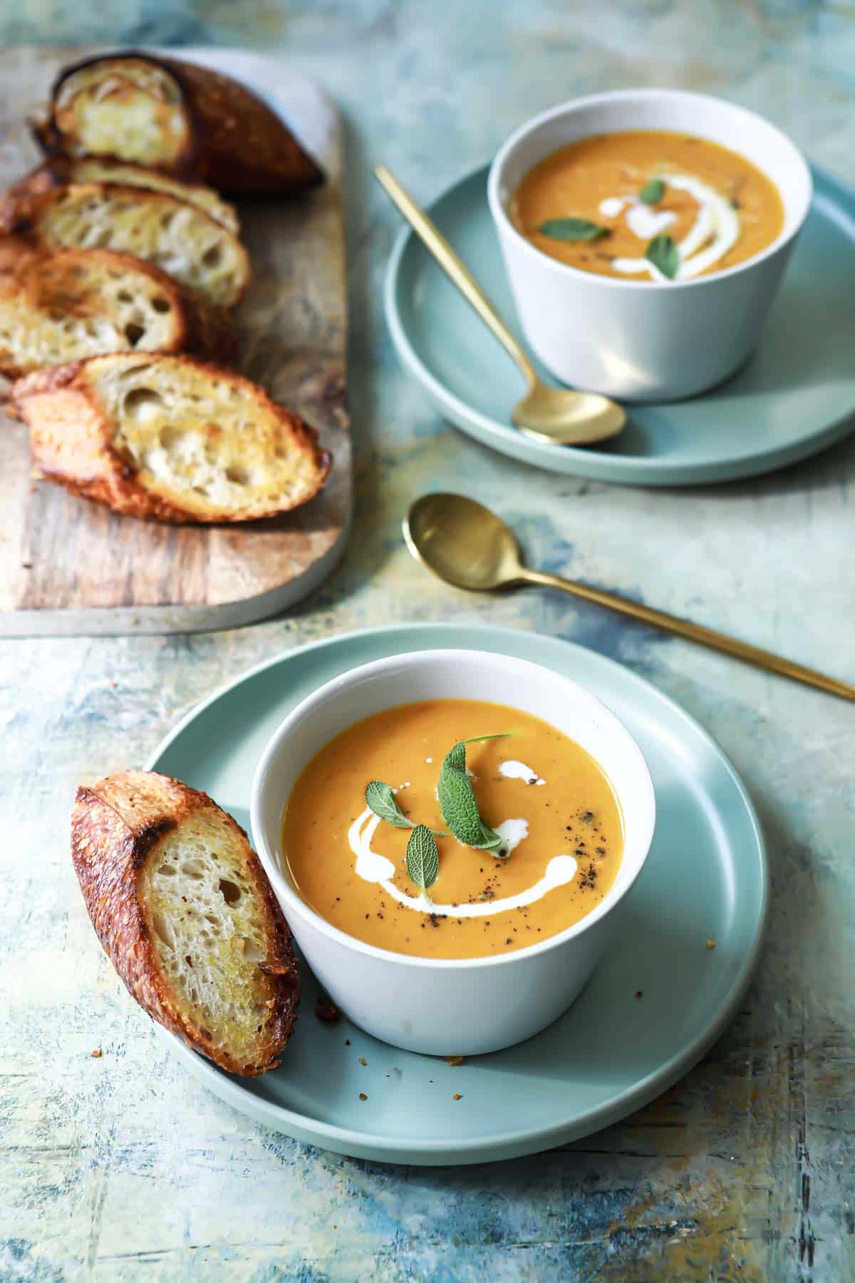 Two bowls of pumpkin soup with garnishes.