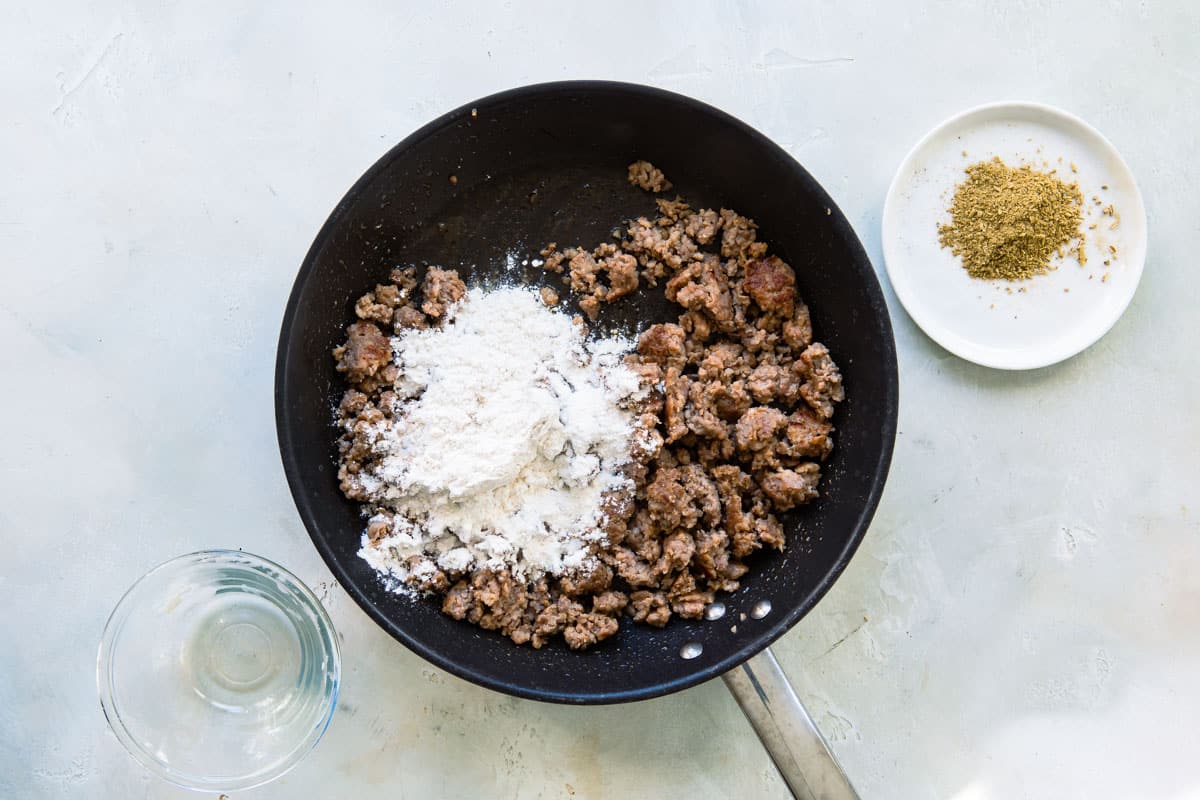 Pork sausage and spices cooking in a skillet.