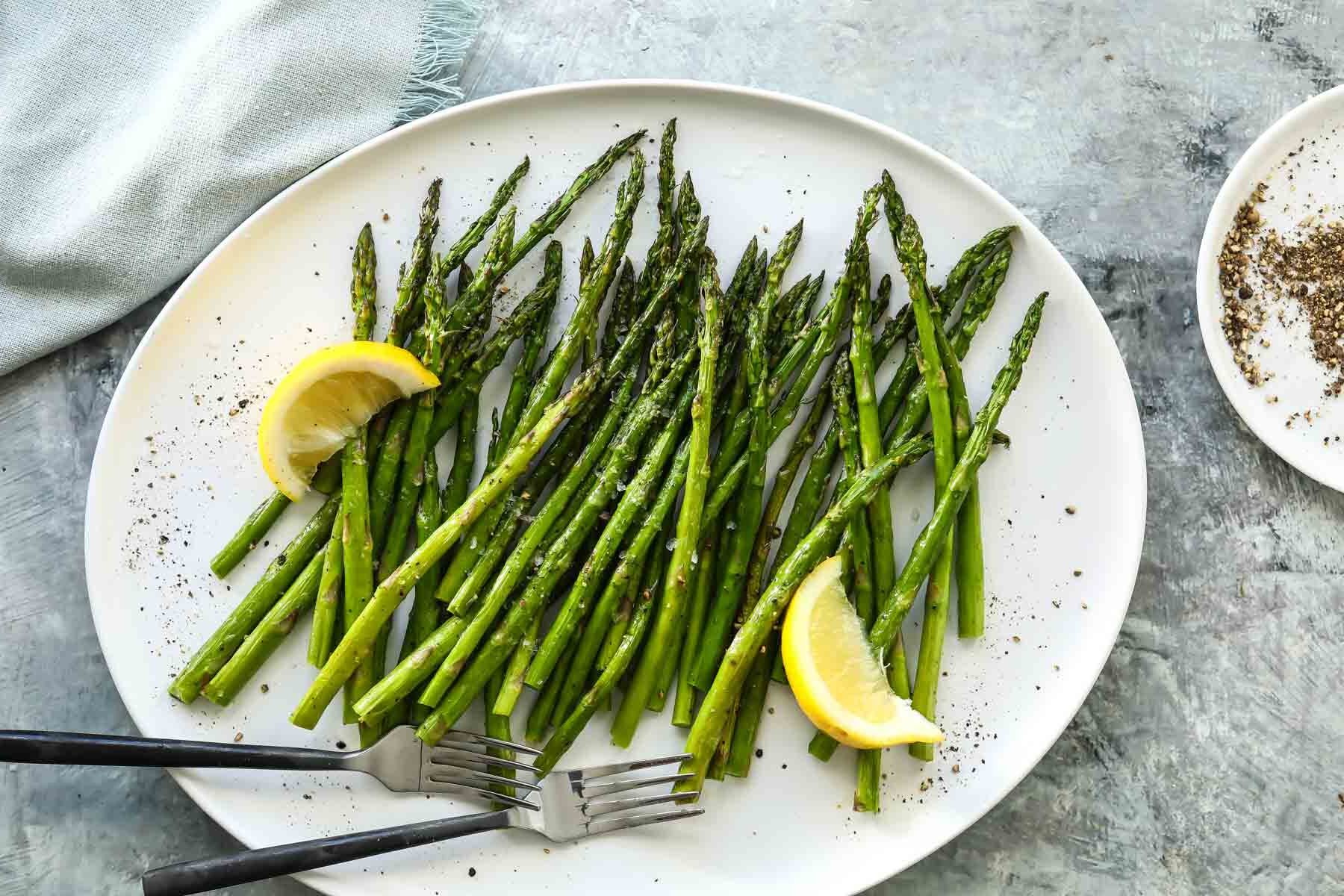 A plate of air fried asparagus with two forks.