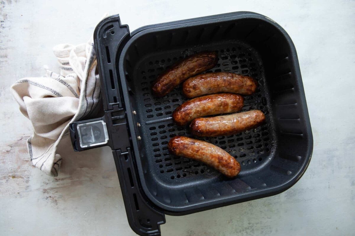 An air fryer basket with air fried brats.