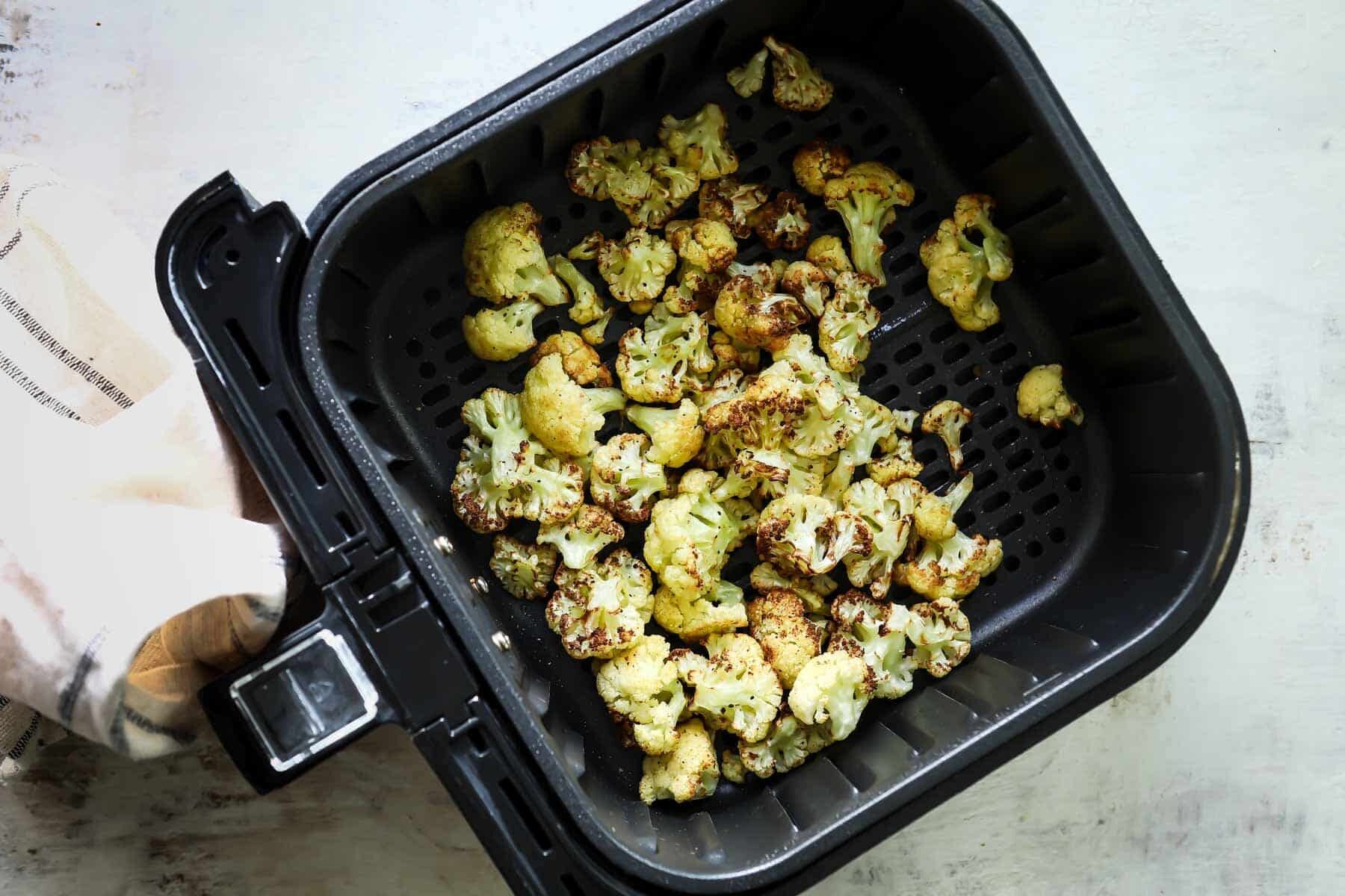 Cauliflower in an air fryer basket.