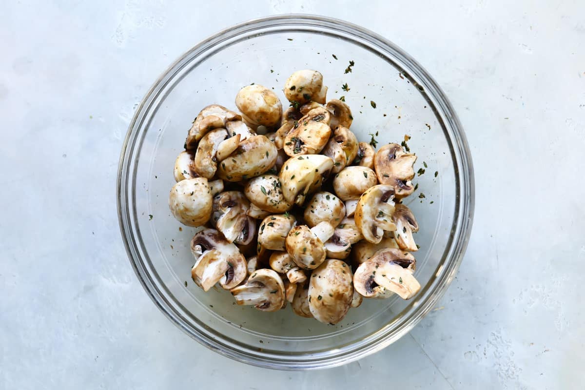 A glass bowl with mushrooms and spices.