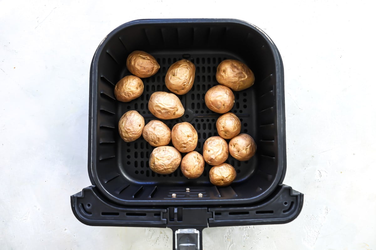 An air fryer basket with cooked baby potatoes in it.