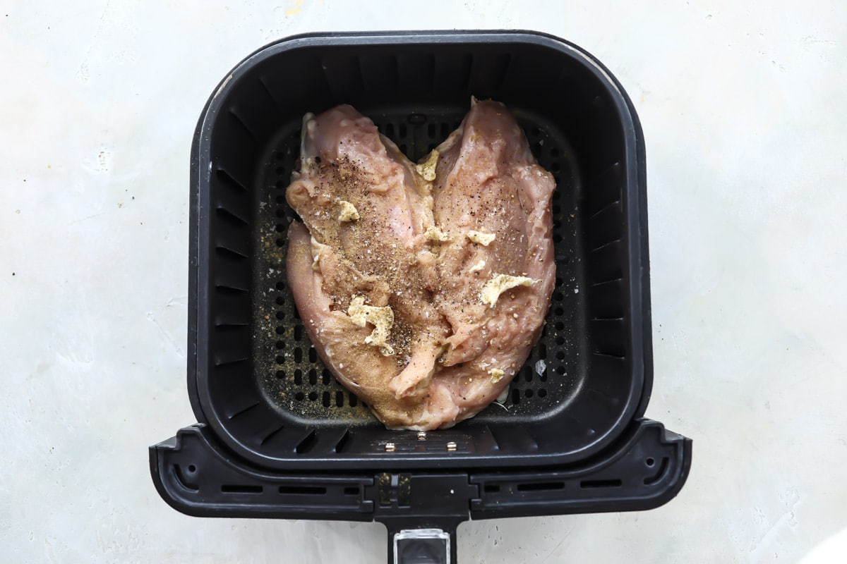 A raw turkey breast in an air fryer basket.