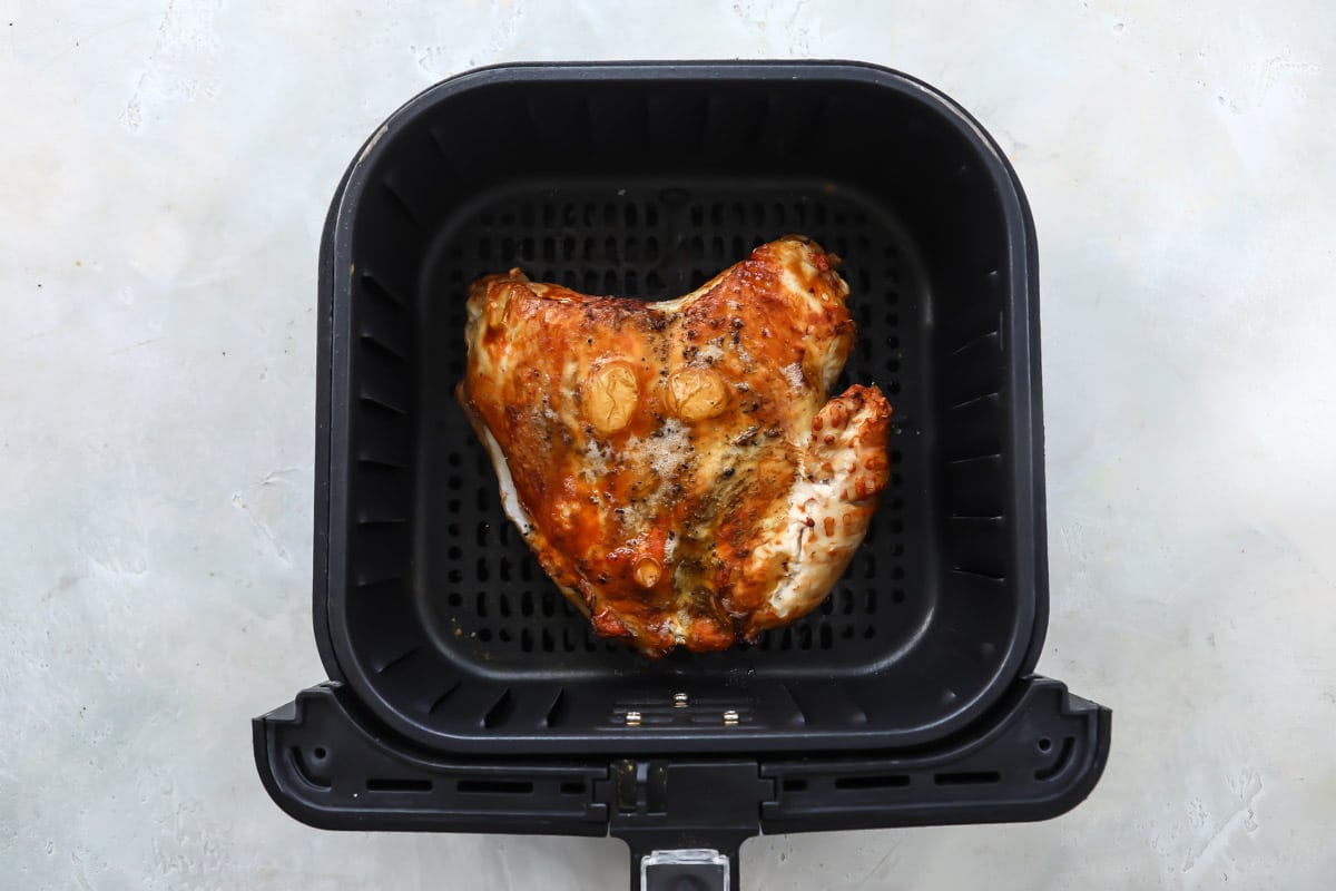 A turkey breast in an air fryer basket after being cooked.