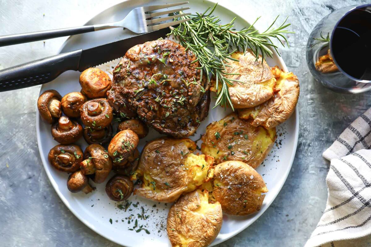 A plate with a filet, mushrooms and smashed potatoes.