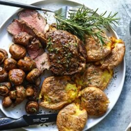 A plate with a filet, mushrooms and smashed potatoes.