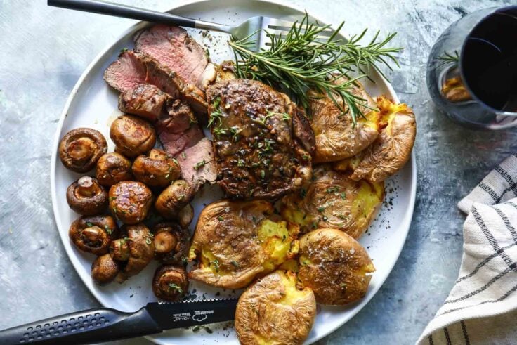 A plate with a filet, mushrooms and smashed potatoes.