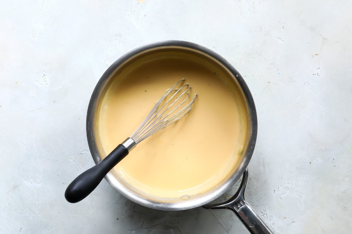 Nacho cheese and a whisk in a saucepan.