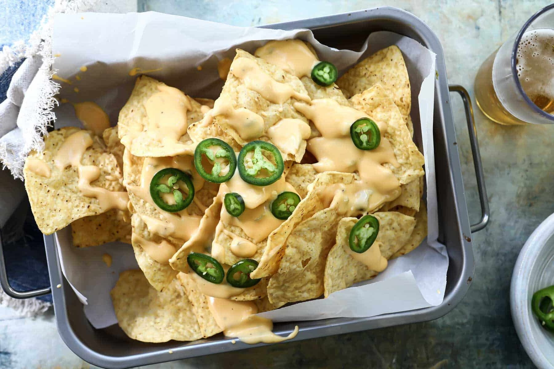 A pan of nachos and cheese and jalapeños.