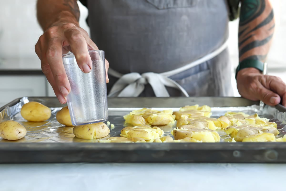 Someone smashing potatoes with the bottom of a cup.