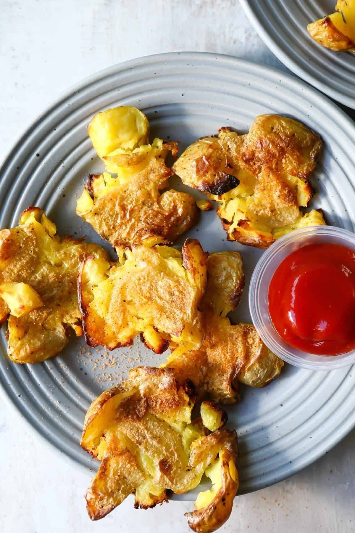 Smashed potatoes on a small gray plate.