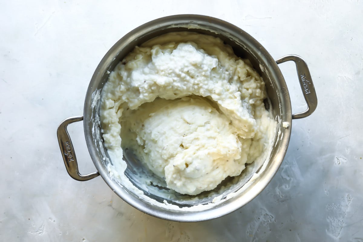 A silver stockpot with sour cream mashed potatoes.