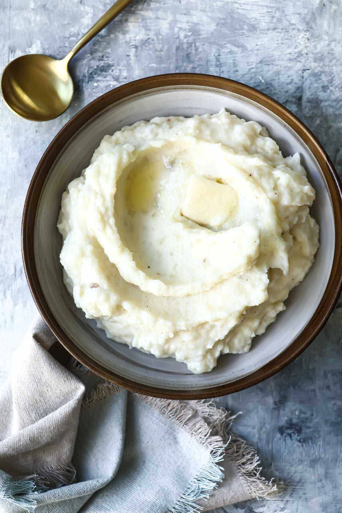 A brown rimmed serving bowl with sour cream mashed potatoes.