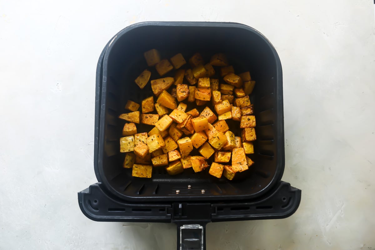 Air fried butternut squash in an air fryer basket.