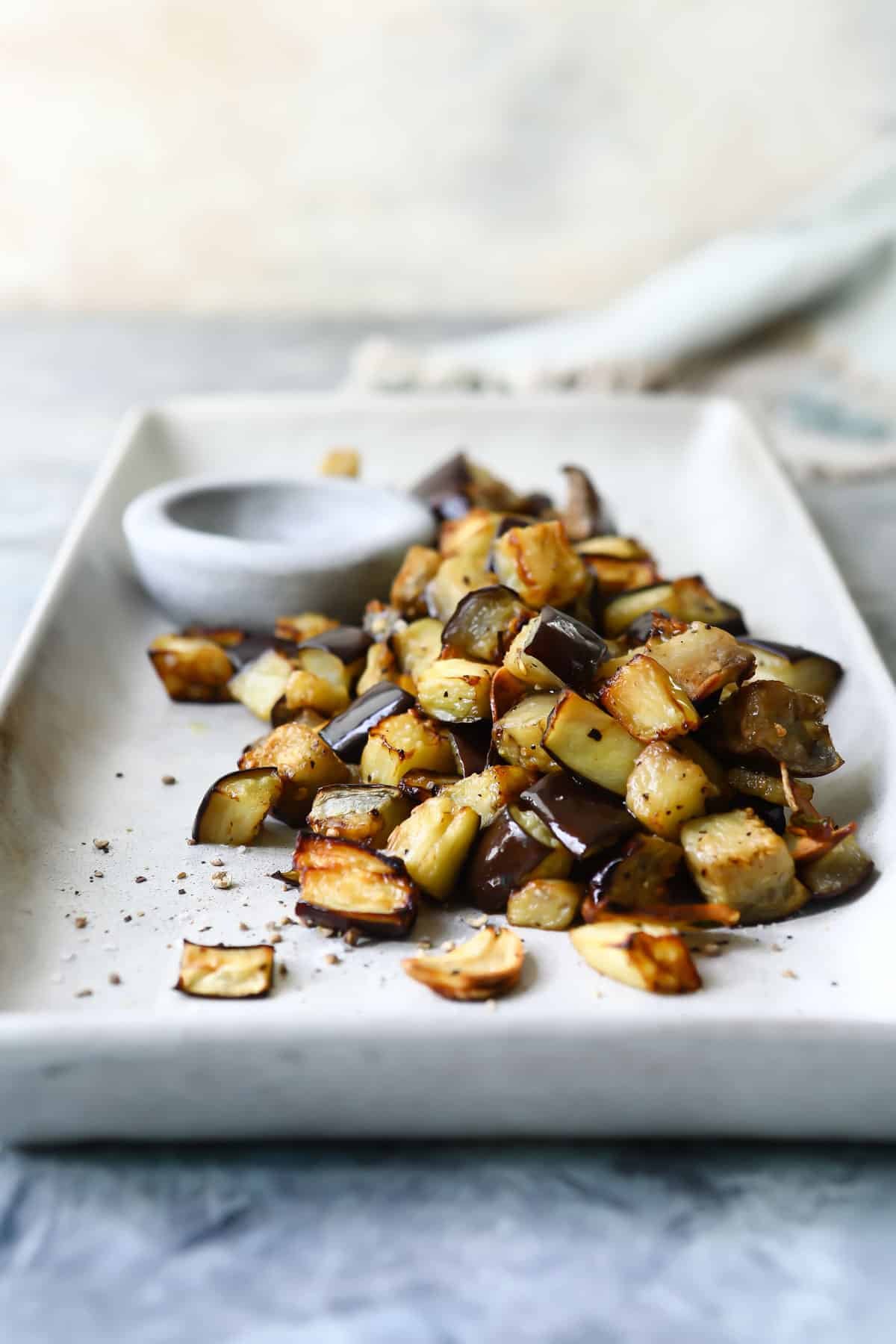 A rectangular serving platter with air fried eggplant on it.