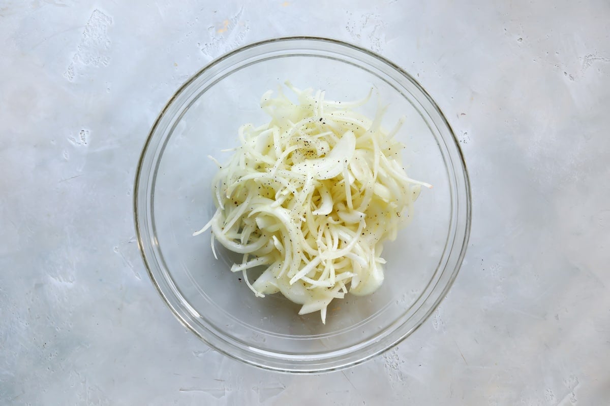 A clear bowl with onions in it.