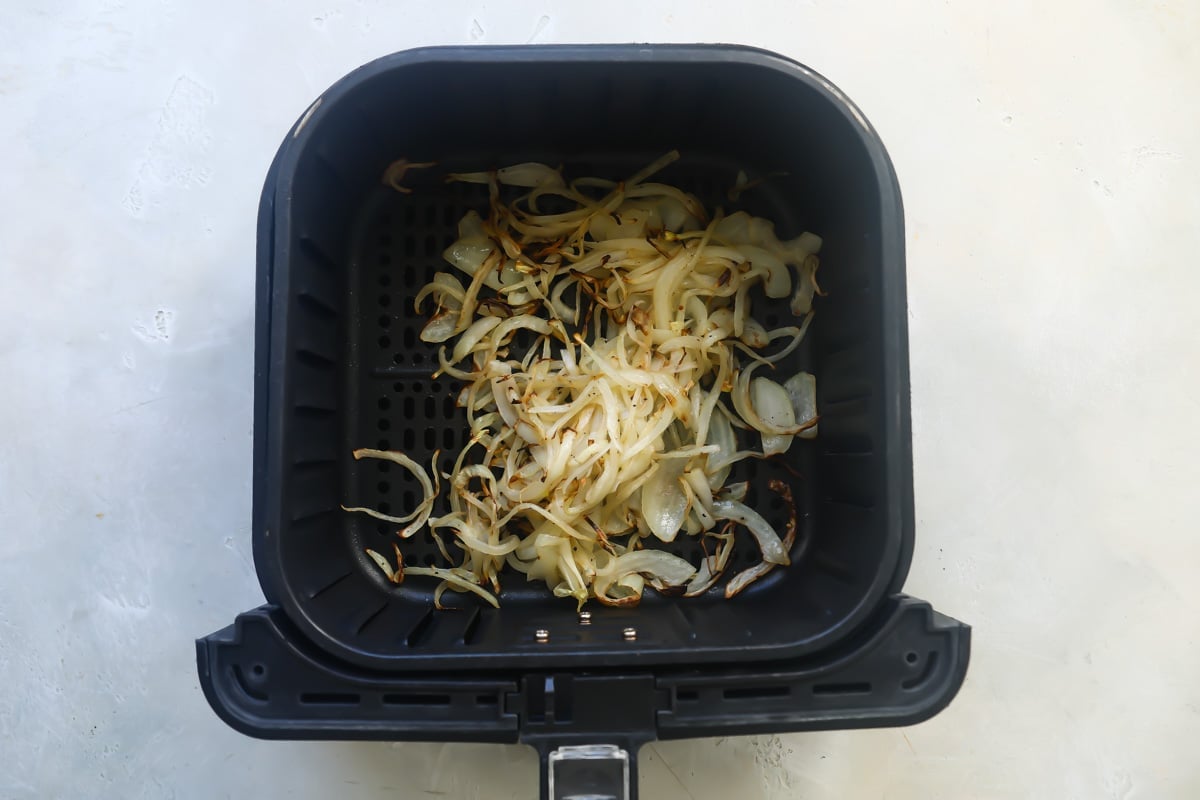 Air fried onions in an air fryer basket.