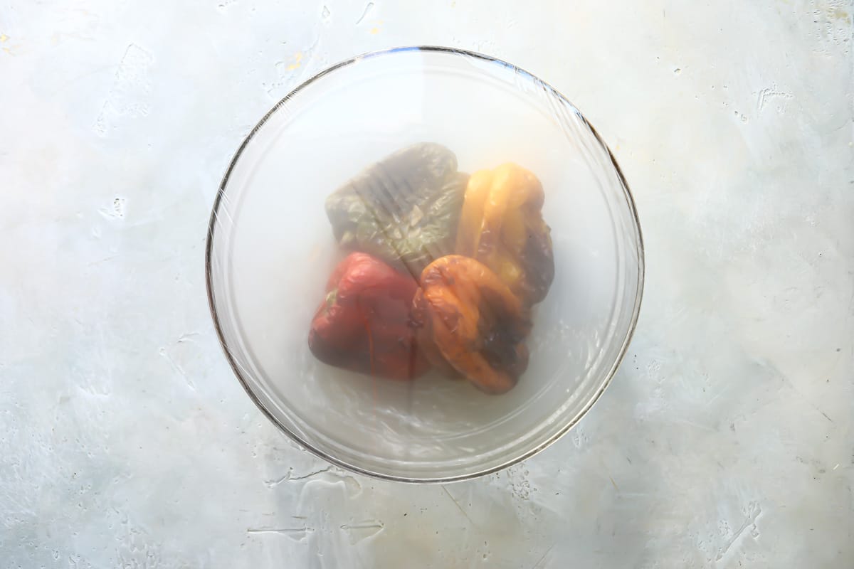 Air fried peppers in a clear bowl covered in plastic wrap.