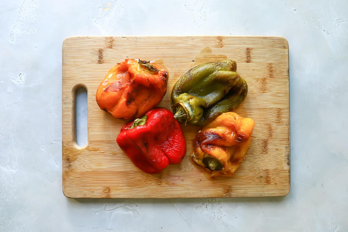 Roasted red peppers on a wooden cutting board.