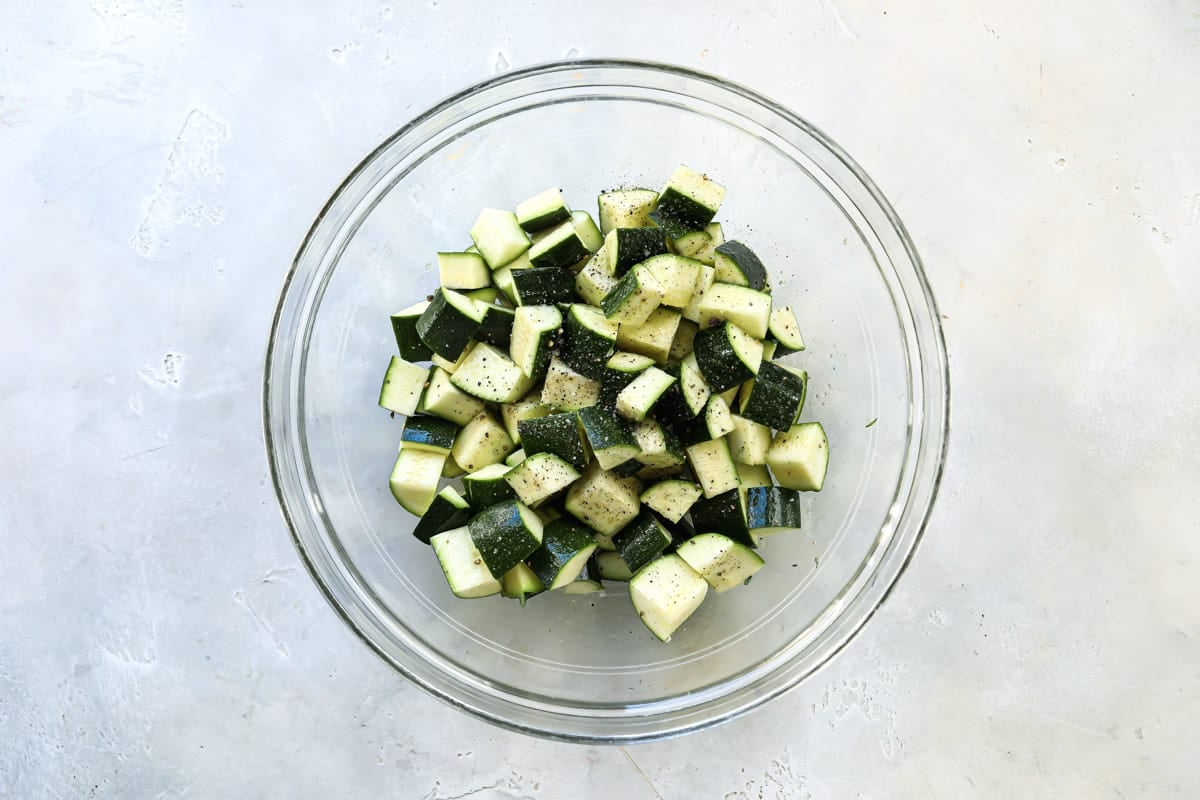 Cubed zucchini in a clear serving bowl.
