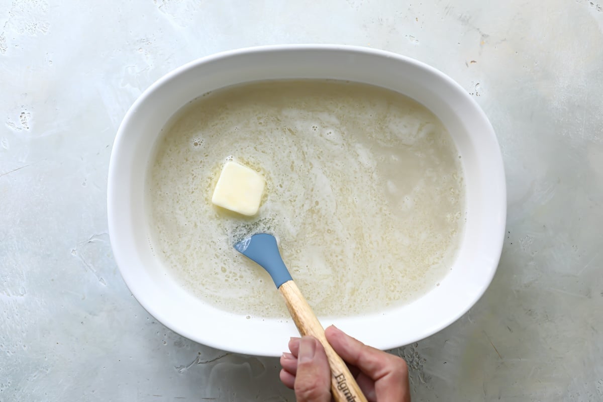 Butter being melted in a baking dish of rice and water.