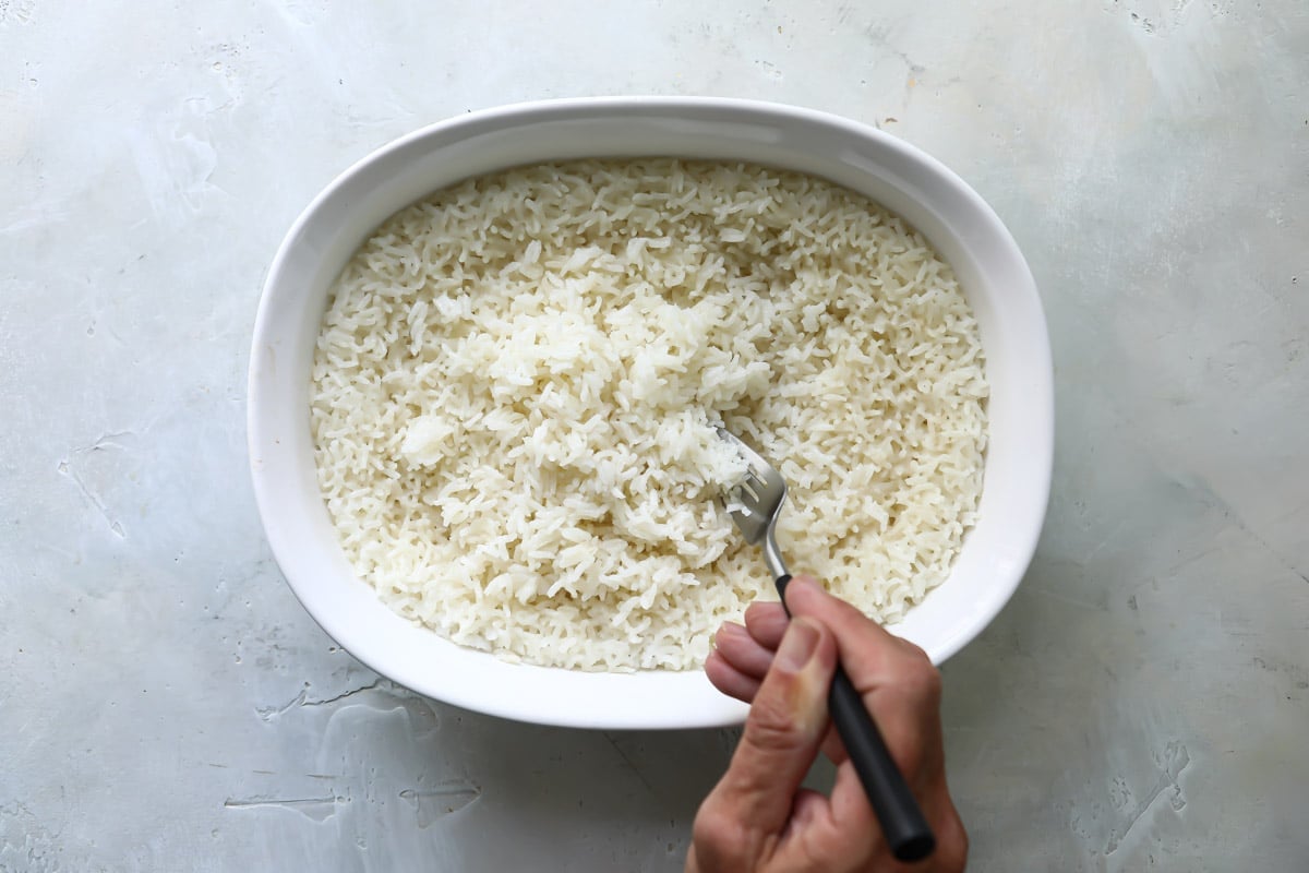 Rice in a baking dish being fluffed with a fork.