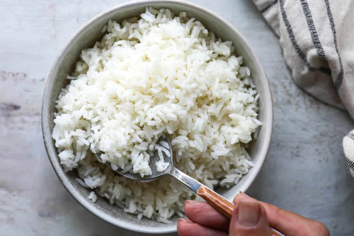 Someone scooping a spoonful of baked rice out of a bowl.