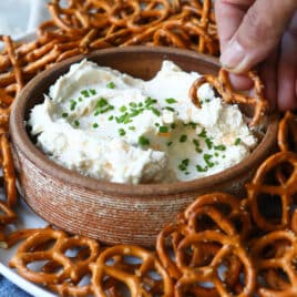 A bowl of beer cheese dip surrounded by pretzels.