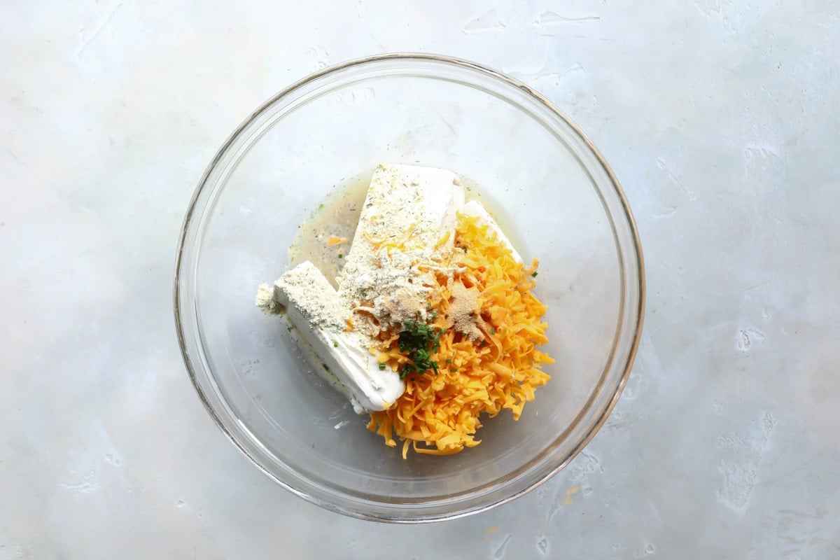 Ingredients for beer cheese dip combined in a bowl.