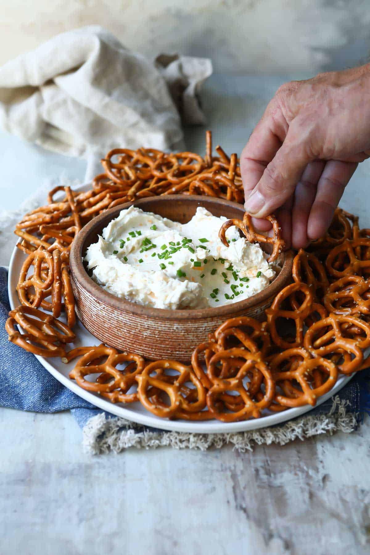 Someone dipping a pretzel in beer cheese dip.