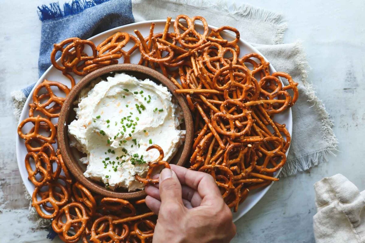 Someone dipping a pretzel in beer cheese dip.