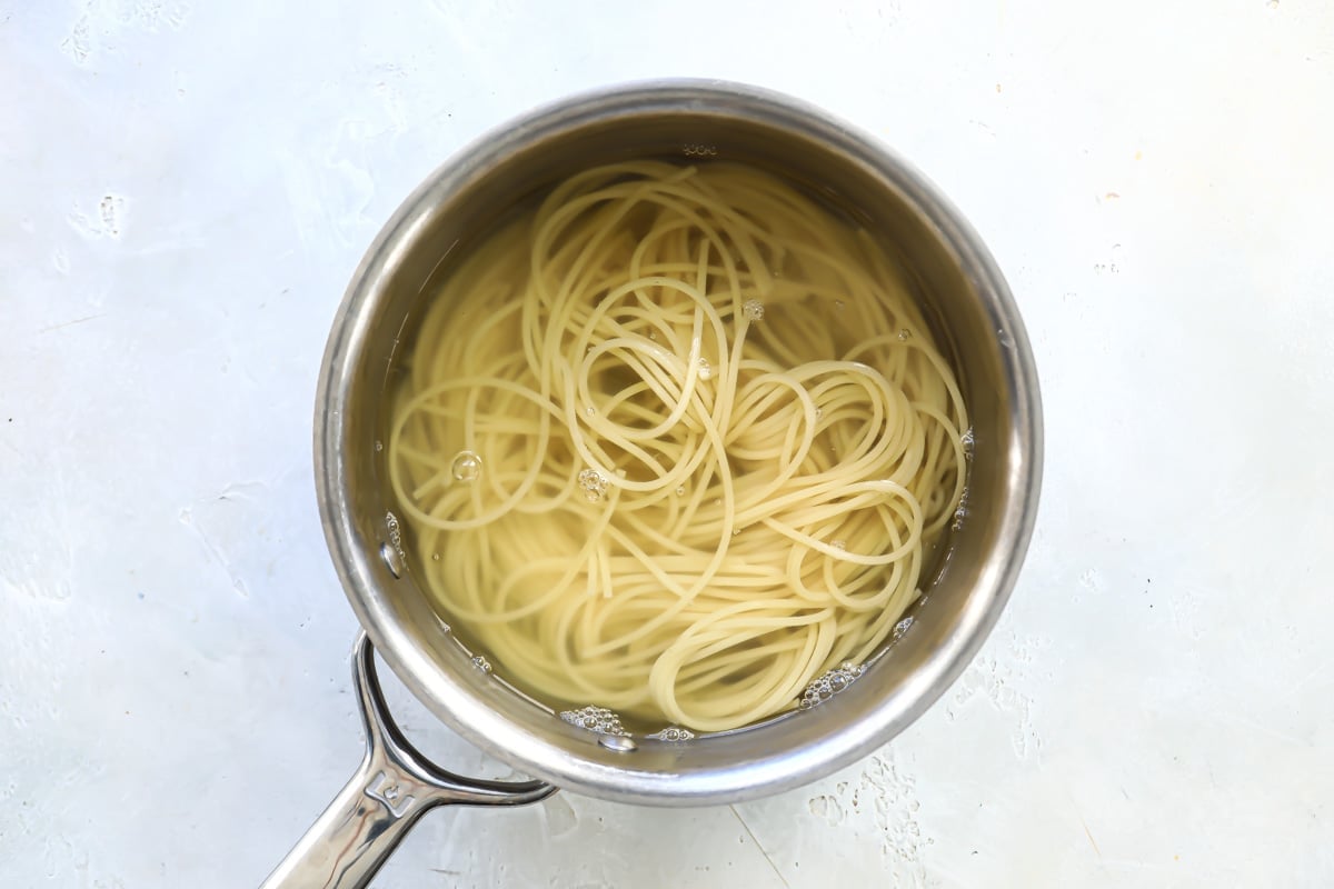 Spaghetti noodles and water in a saucepan.