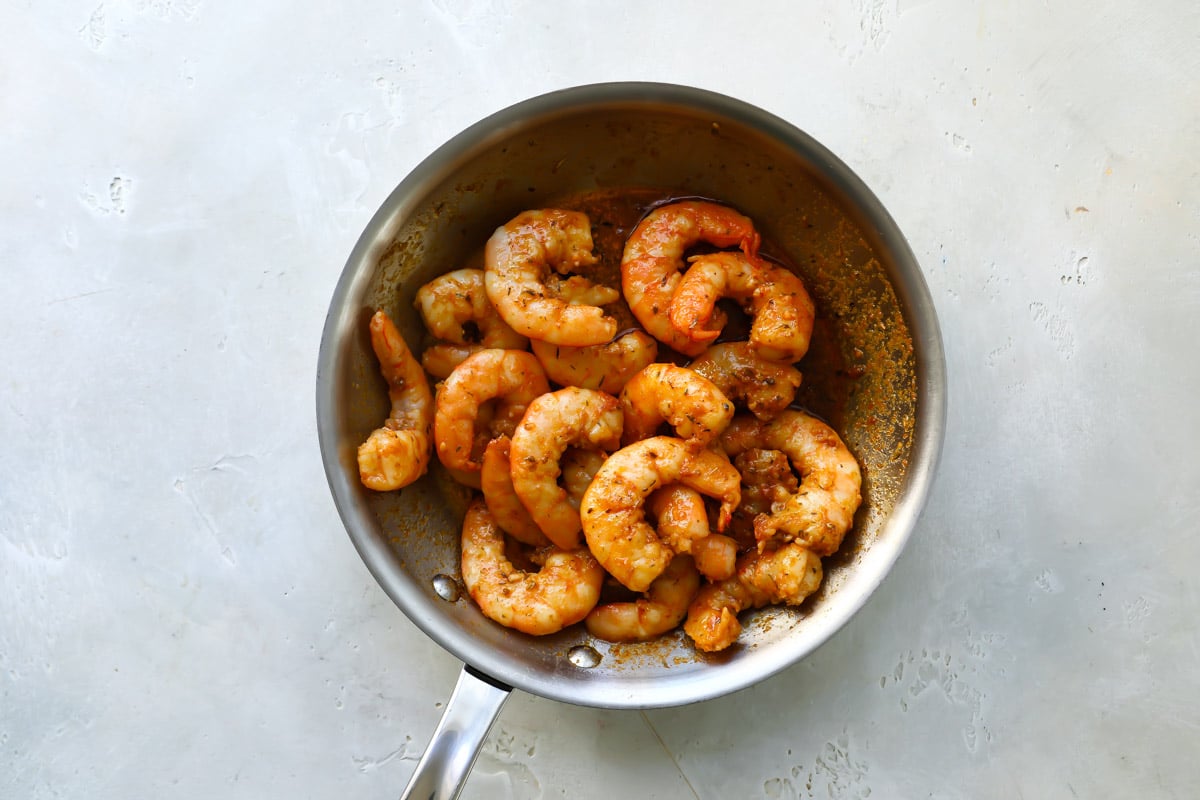 Cajun shrimp being cooked in a silver skillet.