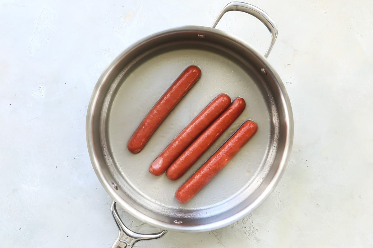Four hot dogs in a skillet.